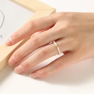 Detail showing a 2mm mini pearl ring with a gold bead on a person's finger