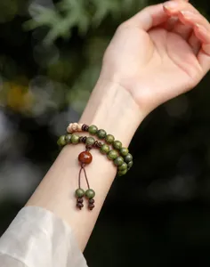 Close-up of a natural green sandalwood prayer bead bracelet on a female wrist.