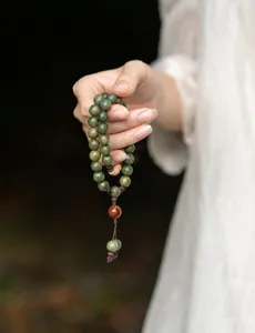 Close-up of green sandalwood Buddhist beads with a traditional red decorative bead.