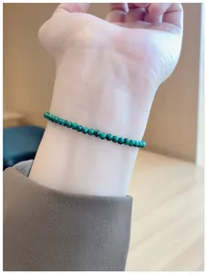 Detailed close-up of a delicate single-strand natural green malachite bead bracelet