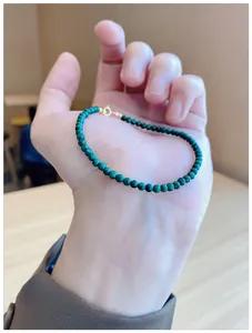 Fine natural green malachite beaded bracelet with gold clasp shown in palm of hand.