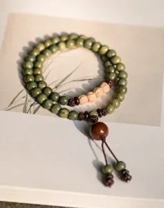 Detailed macro view of 6mm green sandalwood prayer beads with natural wood grain texture.