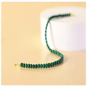 Close-up of a delicate natural green malachite beaded bracelet with a gold clasp