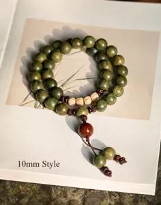 Detailed macro view of 10mm green sandalwood Buddhist prayer beads on a vintage book