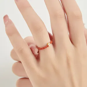 Minimalist 2mm red gemstone beaded ring with a gold lucky coin charm shown on a finger