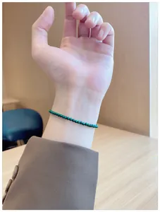 Close-up of a delicate natural green malachite beaded bracelet on a woman's wrist