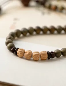 Close-up detail of green sandalwood beads and passion fruit seeds on a bracelet