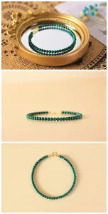 Macro view of a malachite beaded bracelet with gold clasp shown on mirror and beige background