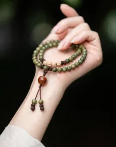 Detail of natural green sandalwood beads and tassel on an ethnic Buddhist mala bracelet