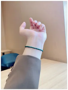 Detailed close-up view of a slim natural green malachite beaded bracelet on a female wrist