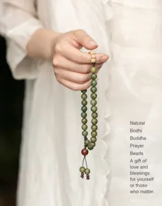 Hand-held close-up of a green sandalwood Buddhist bead bracelet with natural grain