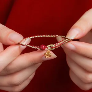 Handgemaakte rood-gouden gevlochten armband met cinnaber kraal en gouden bloembedel