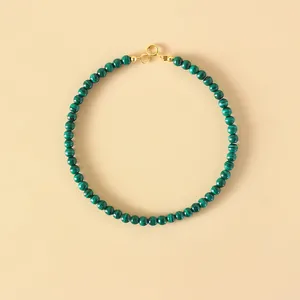 Natural green malachite bead bracelet with gold spring clasp on beige background
