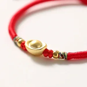 Bracciale artigianale in filo rosso con ciondolo a lingotto d'oro per la fortuna