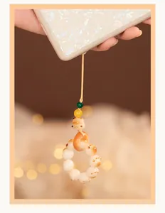 Gros plan d'un mignon pendentif de téléphone en racine de Bodhi blanche en forme de patte
