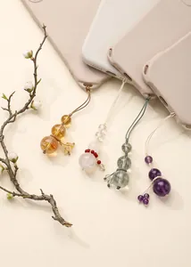 Detail view of various natural crystal gourd phone charms attached to phone cases