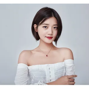 Model wearing a minimalist silver necklace with a round red strawberry crystal pendant