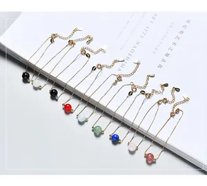 Close-up of elegant gold chain bracelets with various colored natural stone beads.