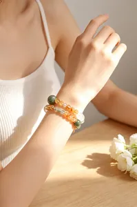 Detalle de una pulsera de cristal de cuarzo amarillo natural en la muñeca de una mujer.