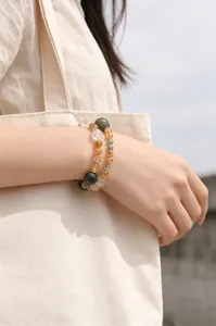 Detalle de elegantes pulseras de cuentas de cristal natural amarillo y blanco en la muñeca