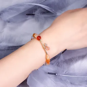Elegant strawberry quartz beaded bracelet with gold star charm worn on female wrist