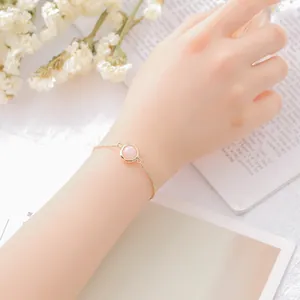 Elegant gold alloy bracelet featuring a round pink strawberry crystal worn on a wrist.