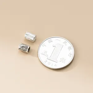 Detailed view of 925 sterling silver leaf pattern tube beads with coin for scale