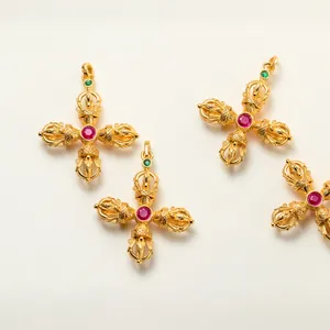 Detail view of gold-plated 925 silver Vajra cross pendants with red corundum stones.