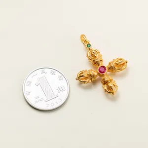 Detailed view of a gold-plated Vajra pendant with red corundum inlay on a beige background
