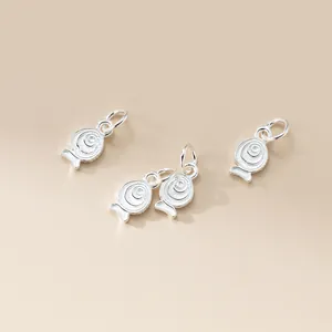 Macro view of S925 sterling silver fish charms with spiral patterns for DIY jewelry.