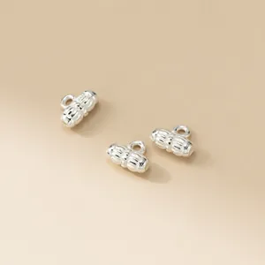 Close-up of three distressed silver DIY spacer bead charms with loops for jewelry making details.