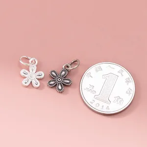Close-up of 925 sterling silver flower charms next to a coin for size reference