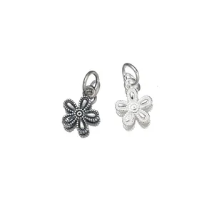 Close-up of vintage S925 sterling silver five-petal flower charms showing metal texture