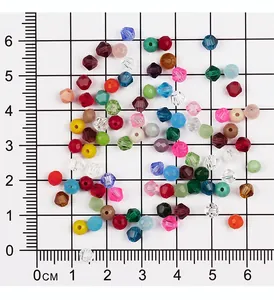 Detailansicht von 4 mm bunten facettierten Bicone-Glasperlen auf einem präzisen Messgitter