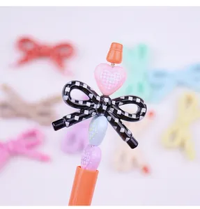Primo piano di perline acriliche a quadretti con fiocco e cuore per accessori gioielli DIY