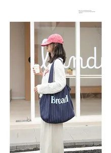 Casual blue striped canvas tote bag with 'Bread' print shown being worn on shoulder.