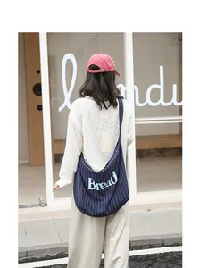 Close-up of navy blue striped canvas tote bag with Bread letter print worn by a woman