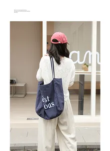 Grand sac cabas en lin bleu marine avec lettrage blanc porté par un mannequin dans la rue