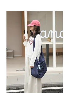 Outdoor lifestyle view of a large navy striped cotton linen tote bag with bold letter print