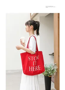 Modella asiatica con una borsa tote in tela rossa e la scritta STOW IT HERE bianca