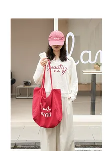 Détail de style d'un grand sac fourre-tout en toile rouge porté par un mannequin