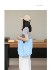 Modelo llevando un bolso tote de nailon azul claro con estampado de corazón y texto.