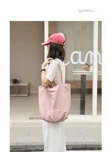 A stylish pink nylon tote bag for women shown on a model in a trendy street setting