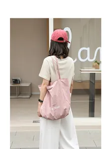Casual pink nylon tote bag with artistic letter print shown on a model from behind