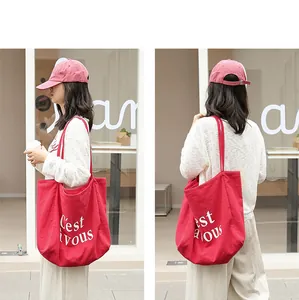 Sac fourre-tout en lin rouge à la mode avec imprimé C'est vous sur un modèle féminin.