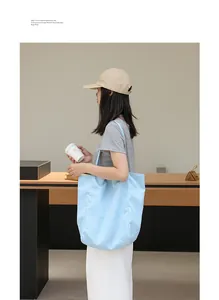 Vista de estilo de vida de un bolso tote de nailon a rayas azul claro llevado por una modelo