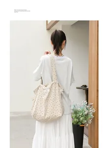 Detalle de bolso tote de lona con lunares y diseño fruncido con cordón en una modelo