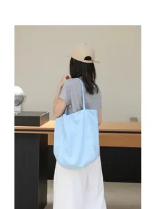 Vista trasera de un bolso tote informal de nailon con rayas azules usado por una modelo.