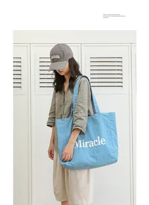 Bolso tote de nailon azul claro con estampado Miracle usado por una modelo con ropa informal