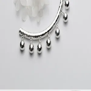 Dettaglio in primo piano di un tubo martellato in argento sterling S925 con campanelle